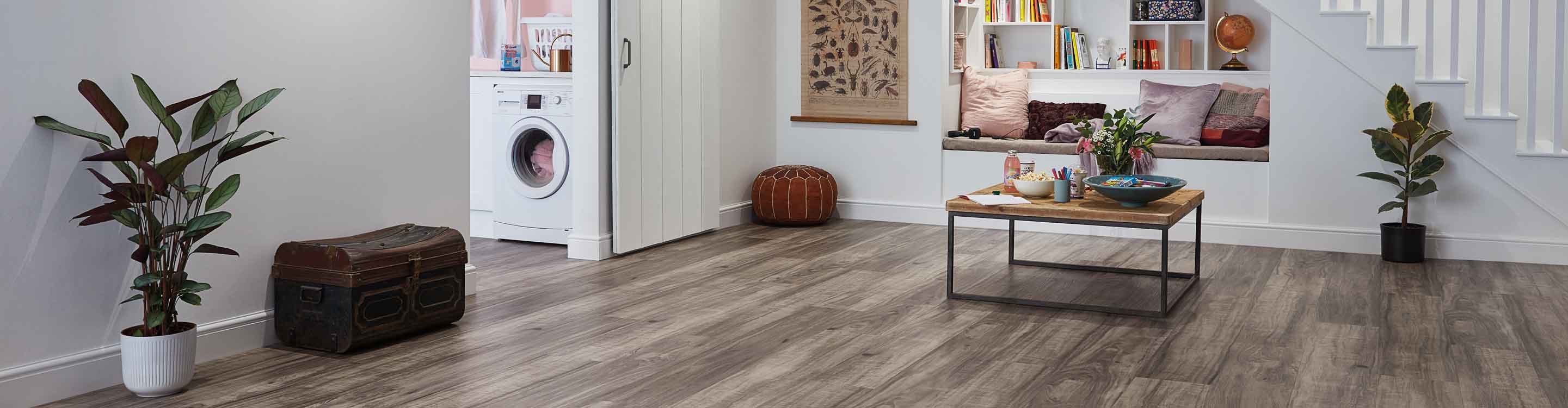 wood look vinyl flooring in finished basement with reading nook, coffee table and barn door leading to laundry room